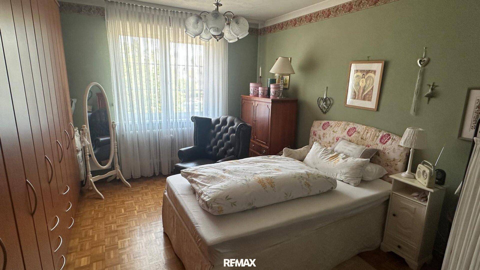 Schlafzimmer mit grün gestrichenen Wänden, Parkettboden und traditionellen Möbeln.