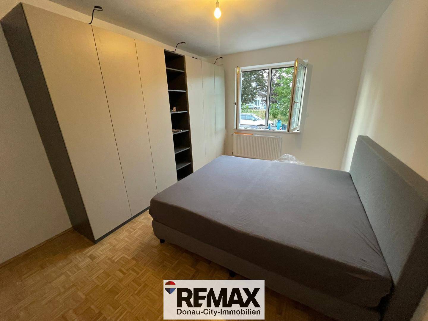 Schlafzimmer mit Bett, Einbauschränken und Fenster, hell und funktional.