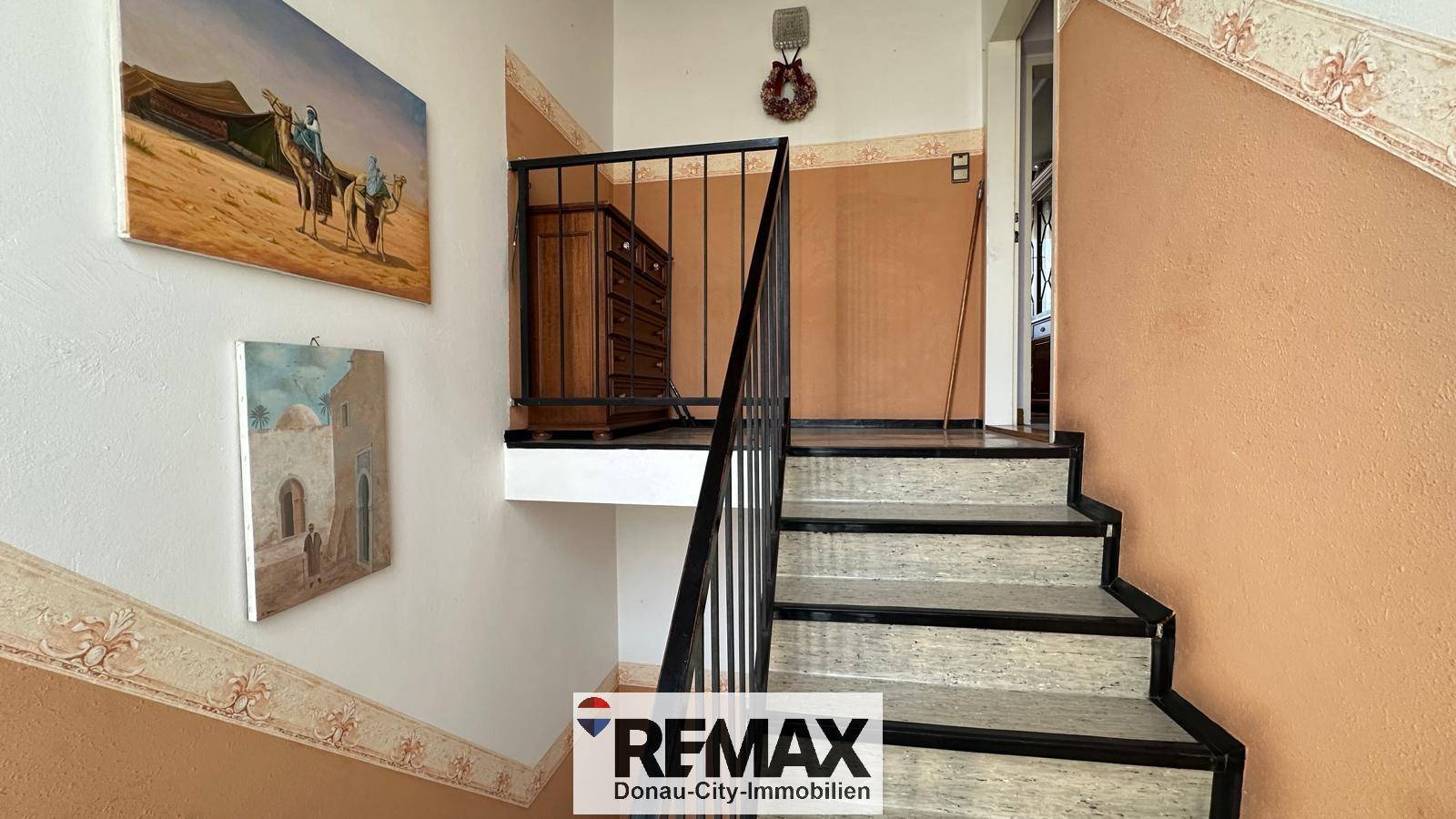 Treppenhaus mit traditionellem Geländer und dekorativen Bildern an der Wand.