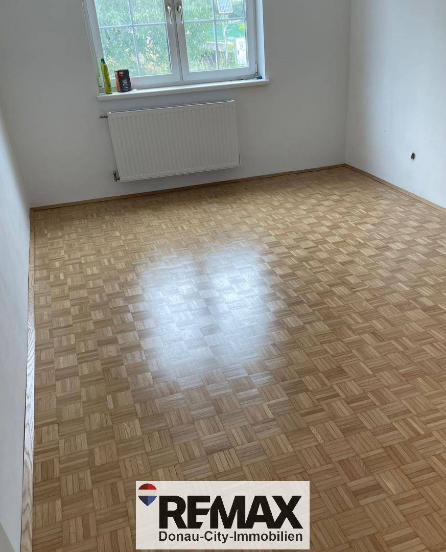Leerer Raum mit Parkettboden und Fenster, bereit zur individuellen Gestaltung.