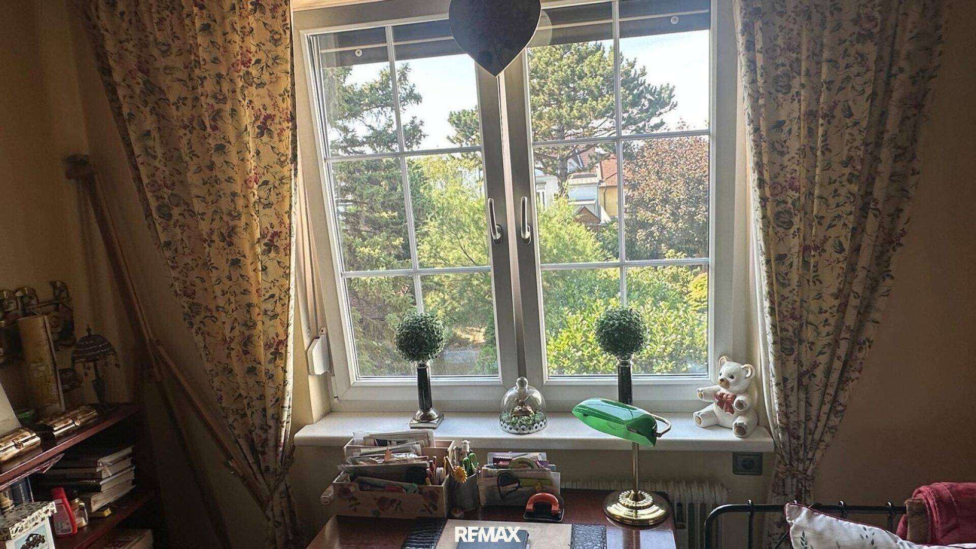 Fenster mit Blick auf grüne Bäume, sorgt für viel natürliches Licht im Zimmer.