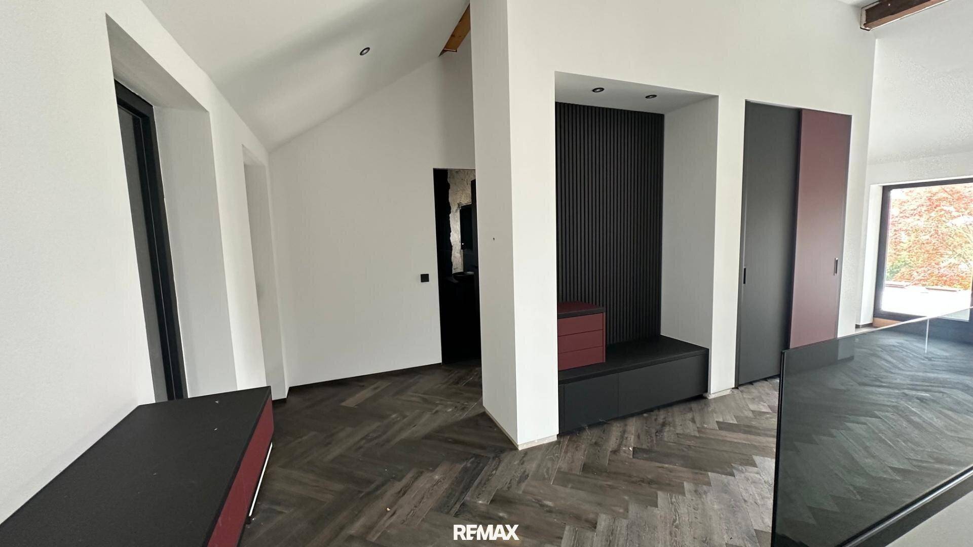 Geräumiger Eingangsbereich mit dunklem Holzfußboden und integrierten Schränken, unter einer Dachschräge.
