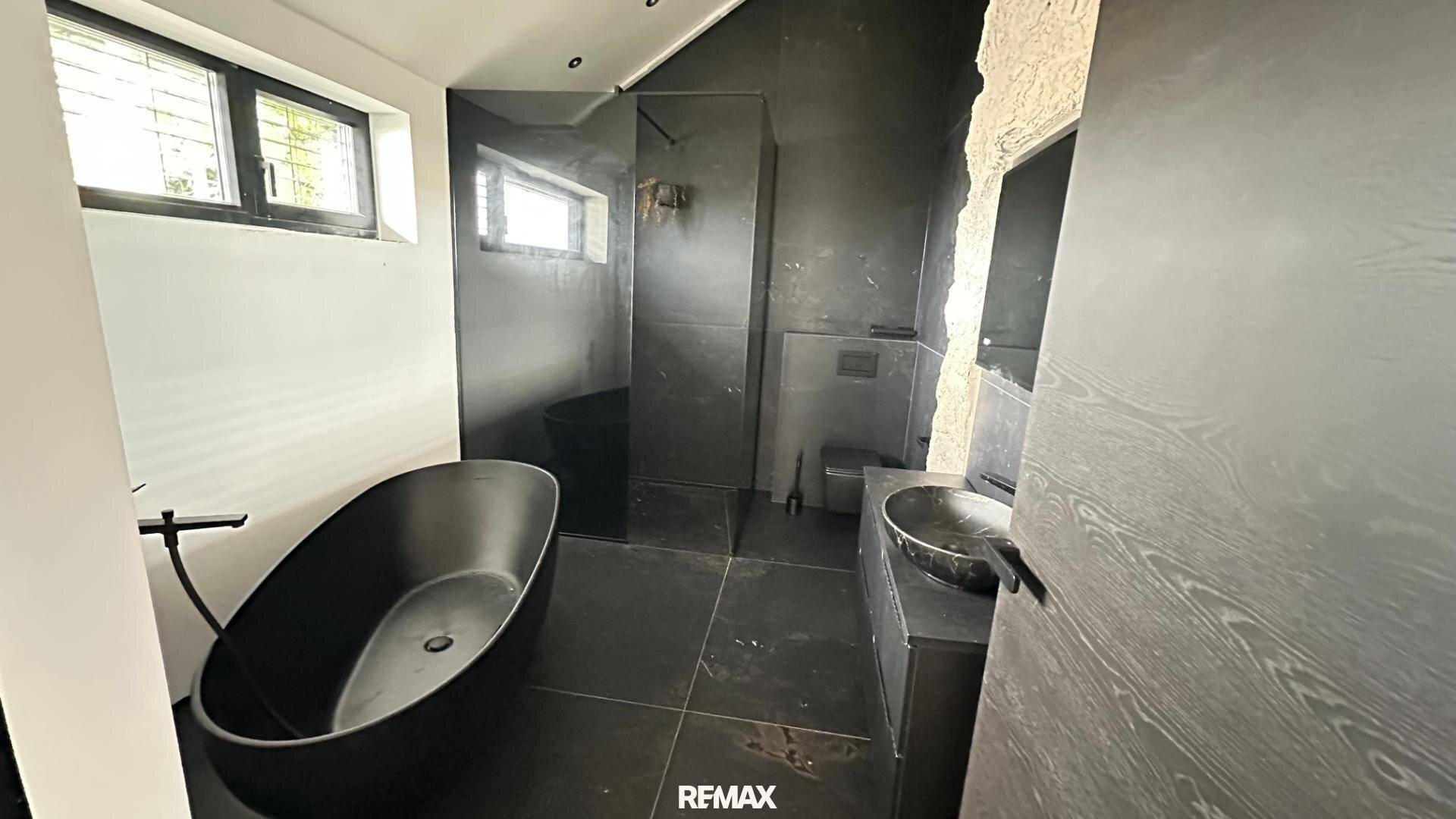 Modernes Badezimmer in dunklen Tönen mit freistehender Badewanne und begehbarer Dusche.