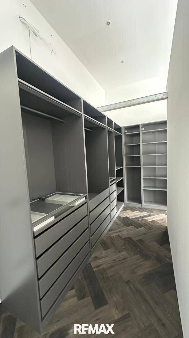 Geräumiger begehbarer Kleiderschrank mit vielen Ablagemöglichkeiten und Schubladen.