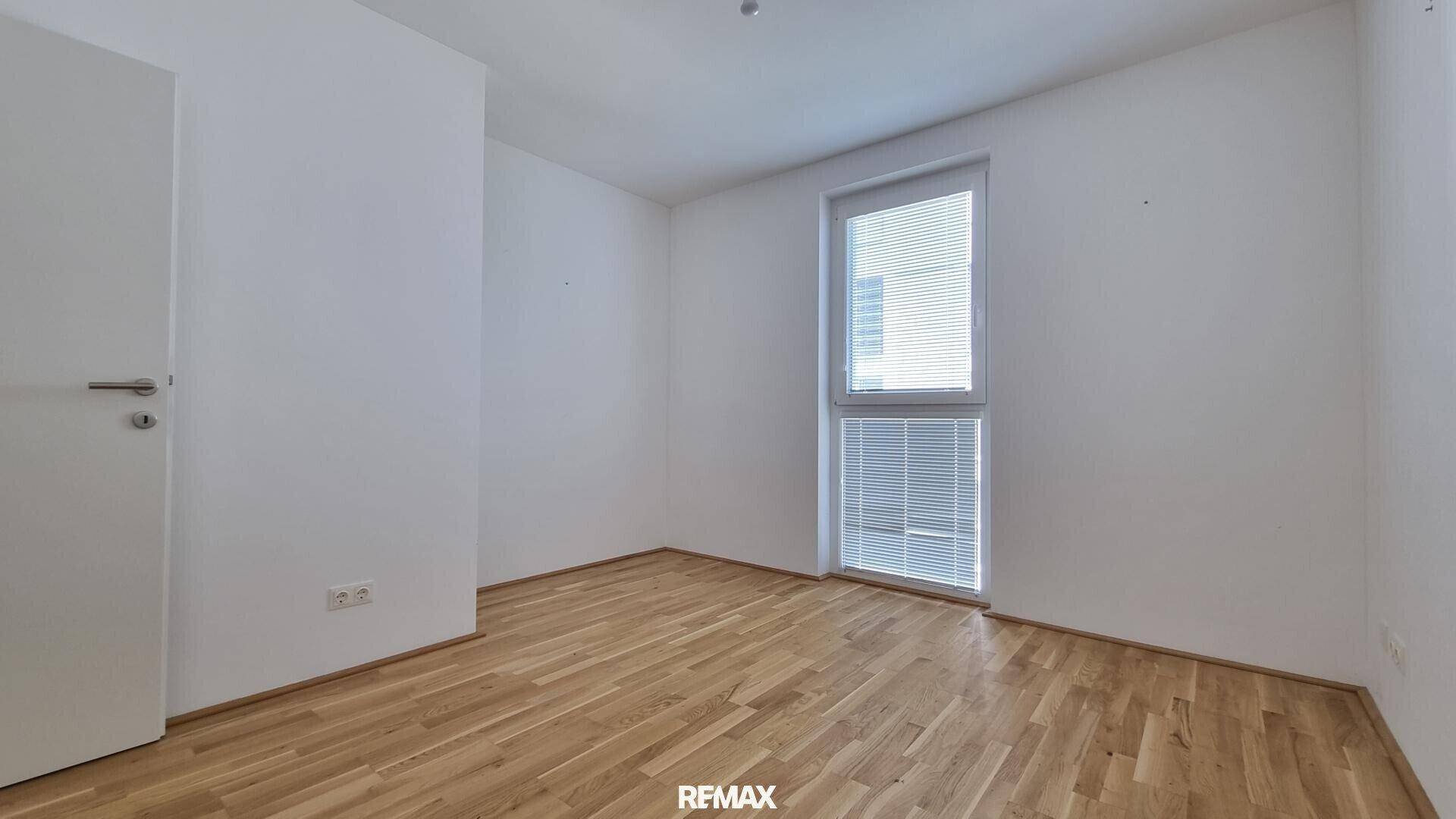 Heller, leerer Raum mit Holzboden und einem Fenster, vielseitig nutzbar als Schlaf- oder Arbeitszimmer.