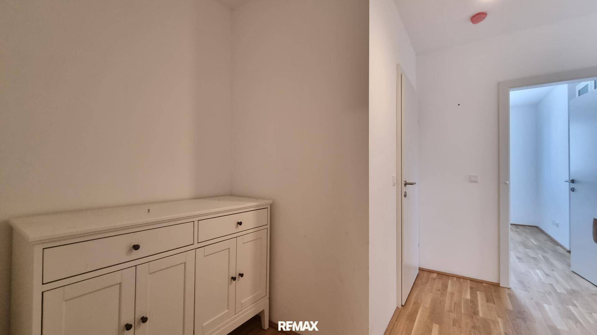 Heller Flur mit Holzboden und einem kleinen Schrank, der zusätzlichen Stauraum bietet.