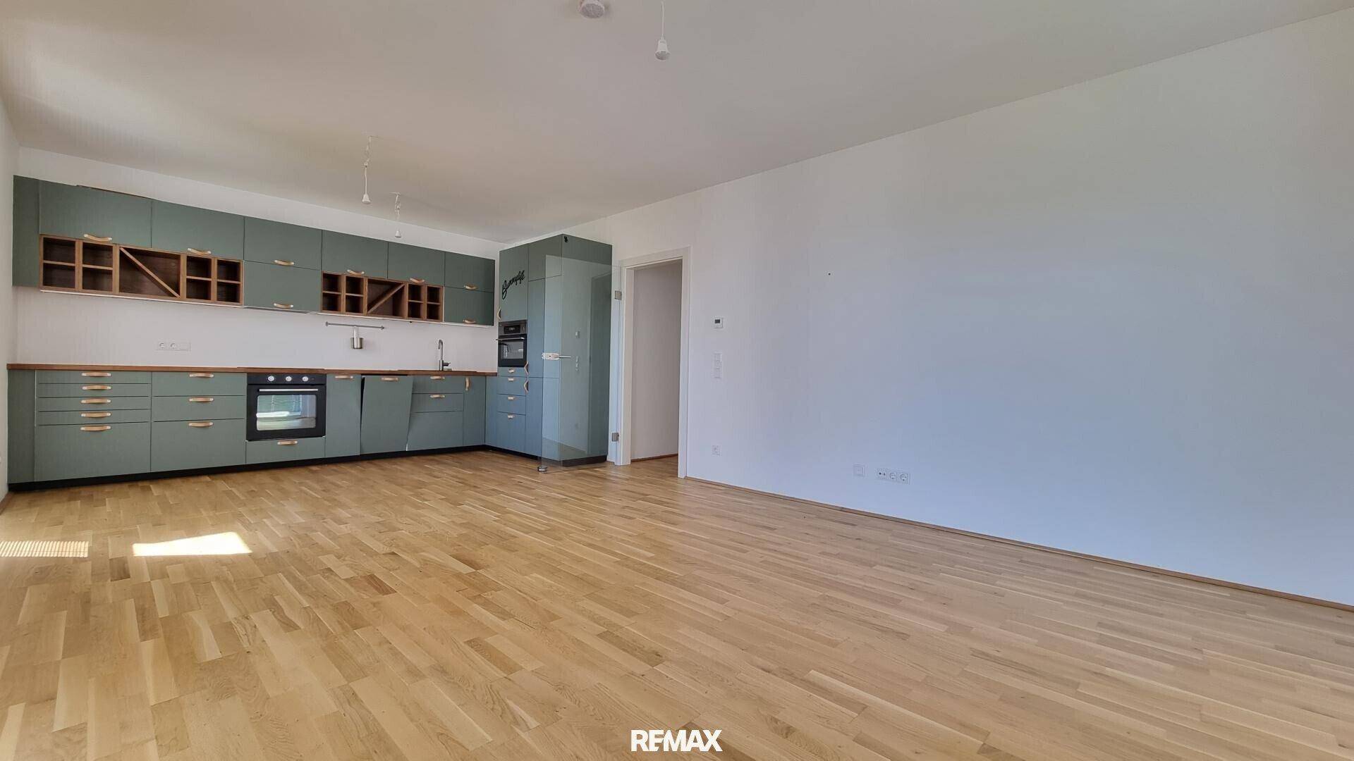 Weitläufiger Wohnbereich mit offener Küche und Holzboden, ideal für geselliges Beisammensein und Kochen.