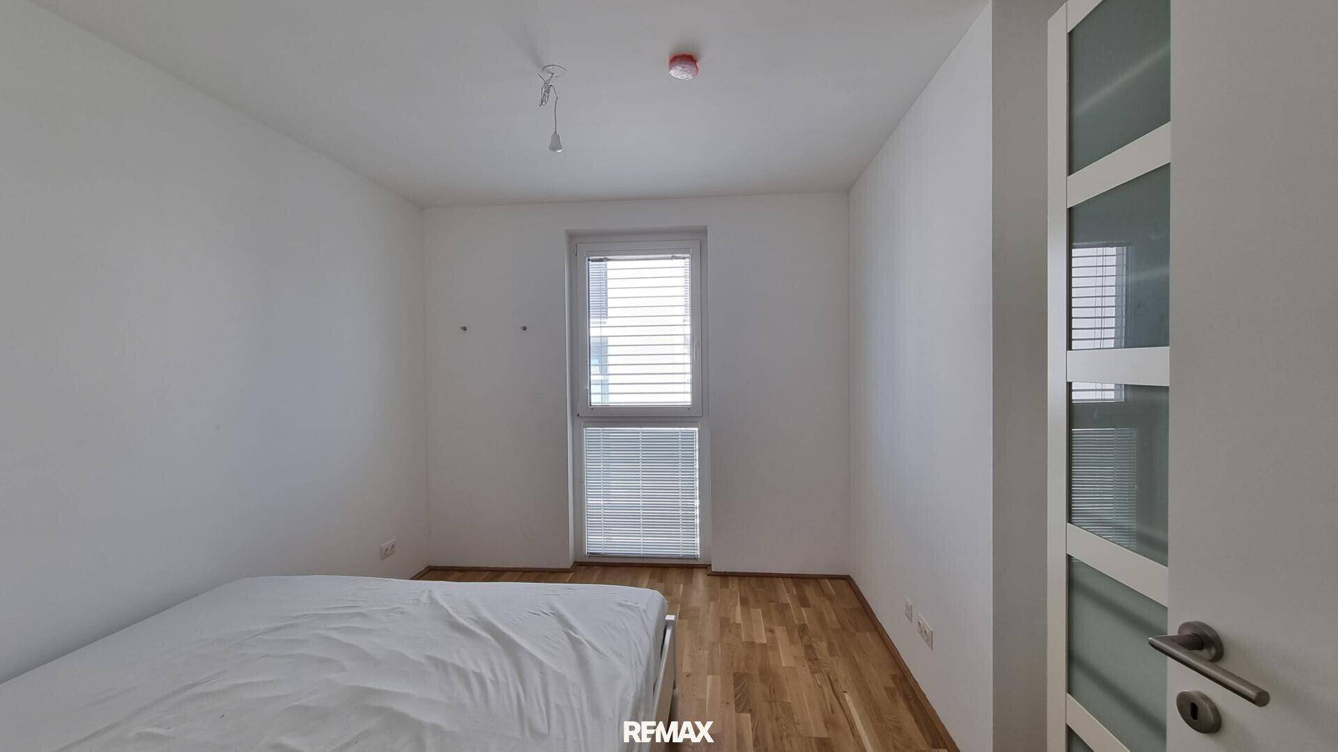 Gemütliches Schlafzimmer mit Holzboden und einem Fenster, das für angenehmes Tageslicht sorgt.