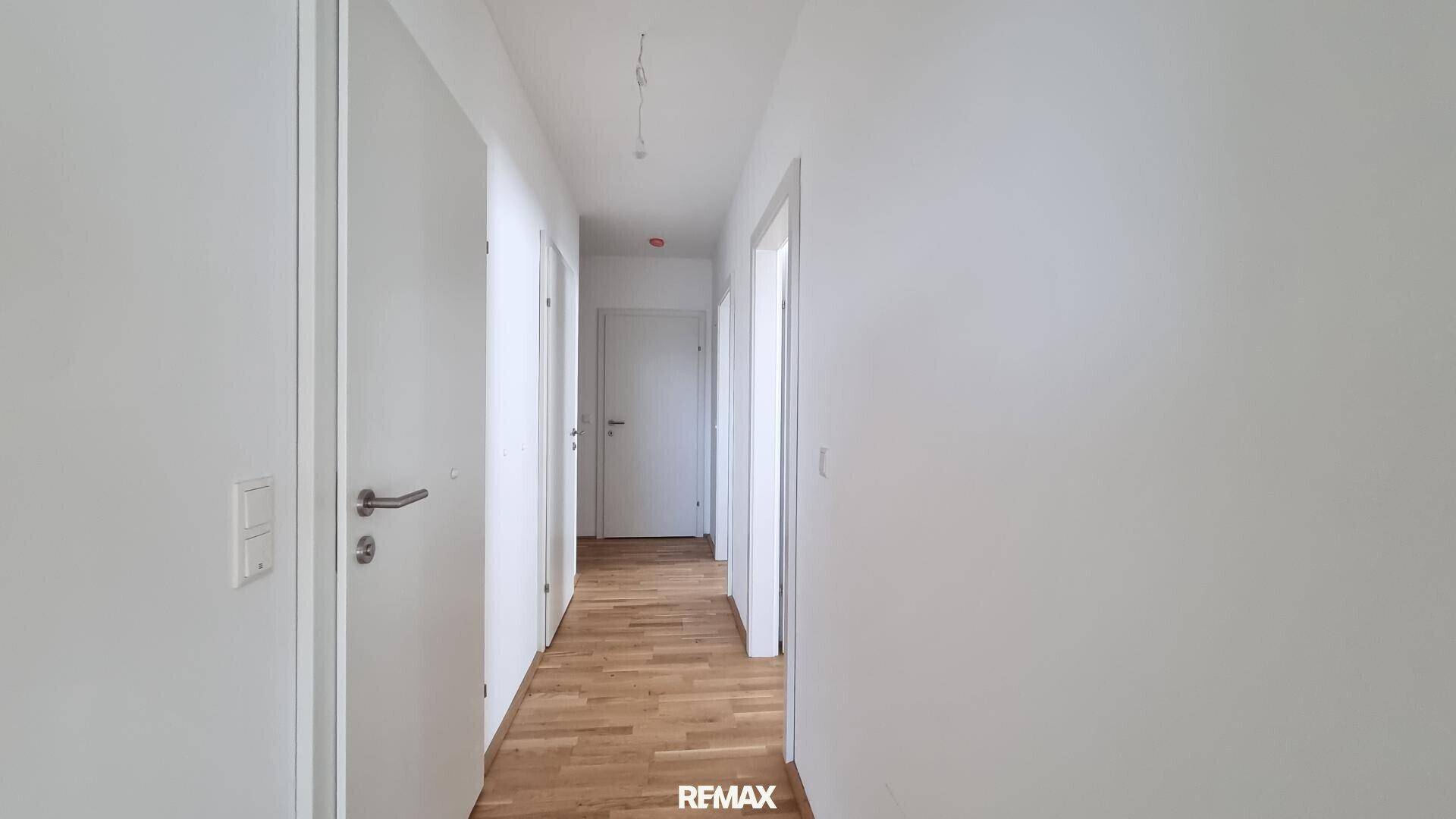 Langer, heller Flur mit Holzboden und mehreren Türen, der die verschiedenen Räume verbindet.