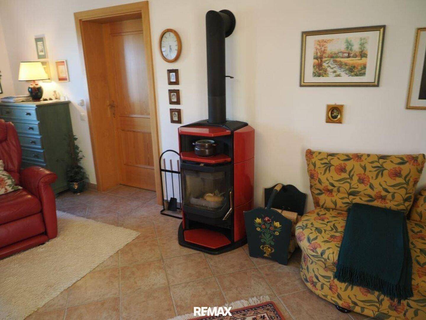 Helles Wohnzimmer mit modernem Kaminofen, Fliesenboden und gemütlichem Sessel.
