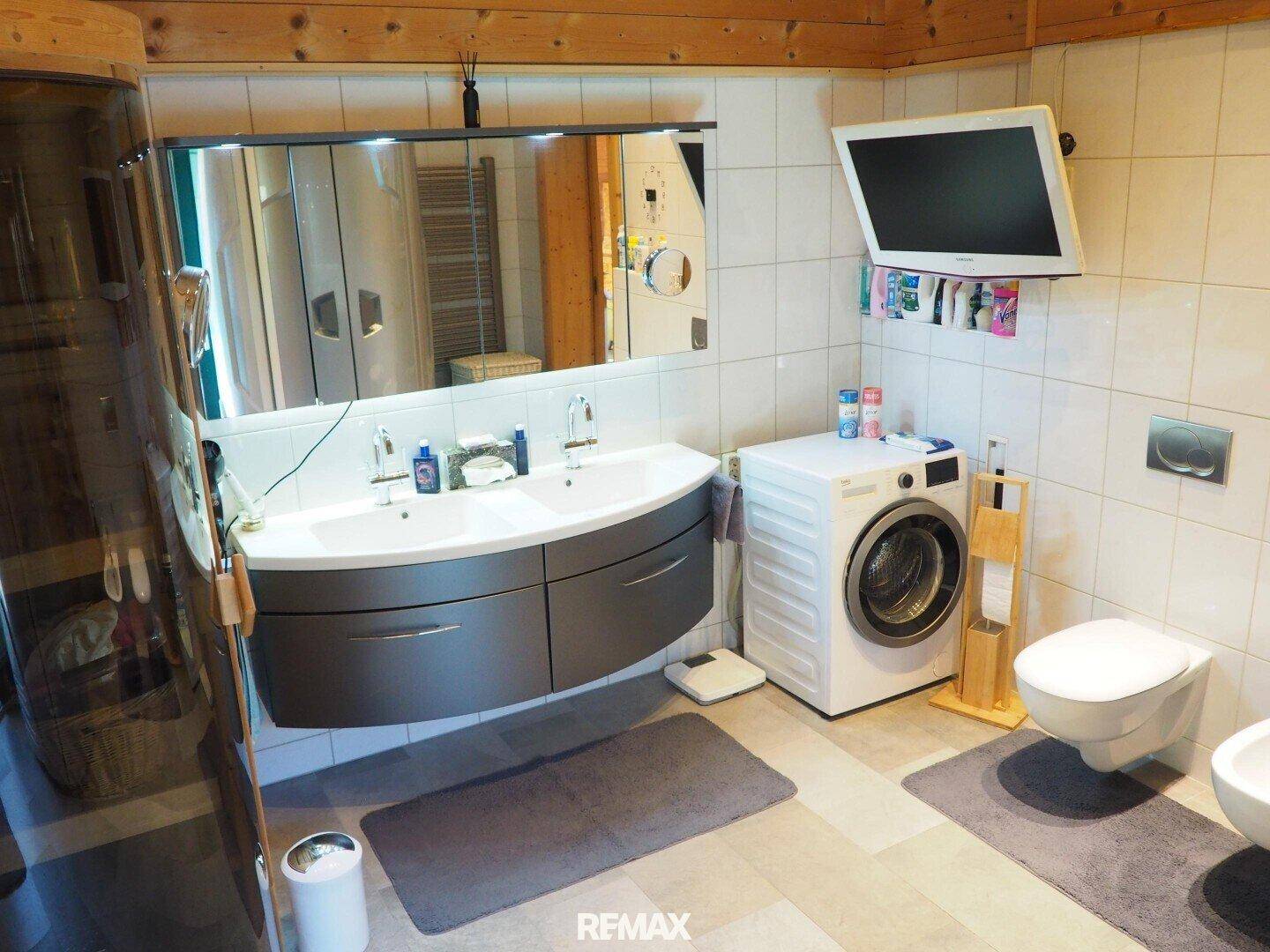 Modernes Badezimmer mit Doppelwaschbecken, Toilette, Bidet und Waschmaschine.