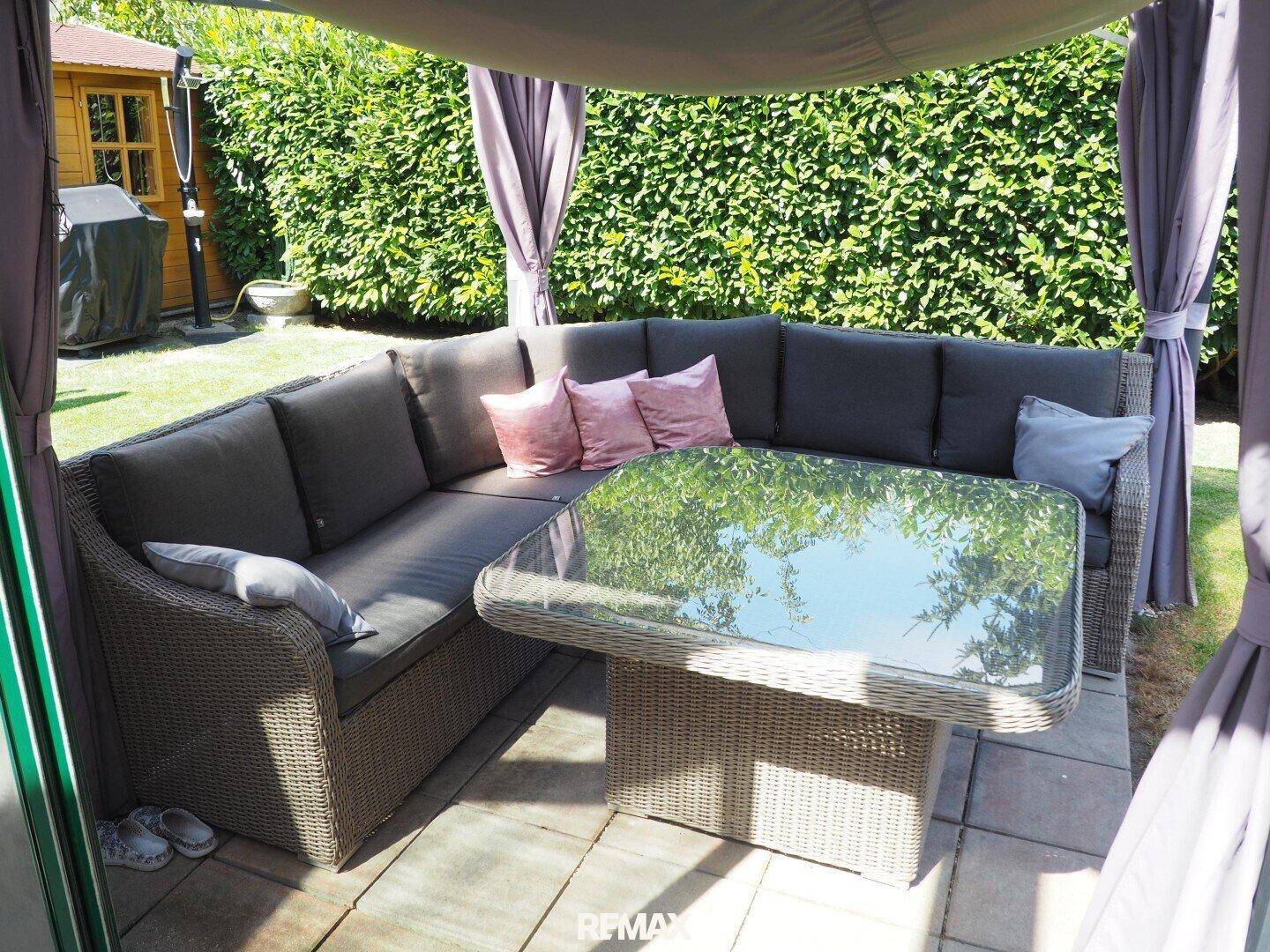 Gemütlicher Outdoor-Sitzbereich unter einem Pavillon mit bequemen Lounge-Möbeln.