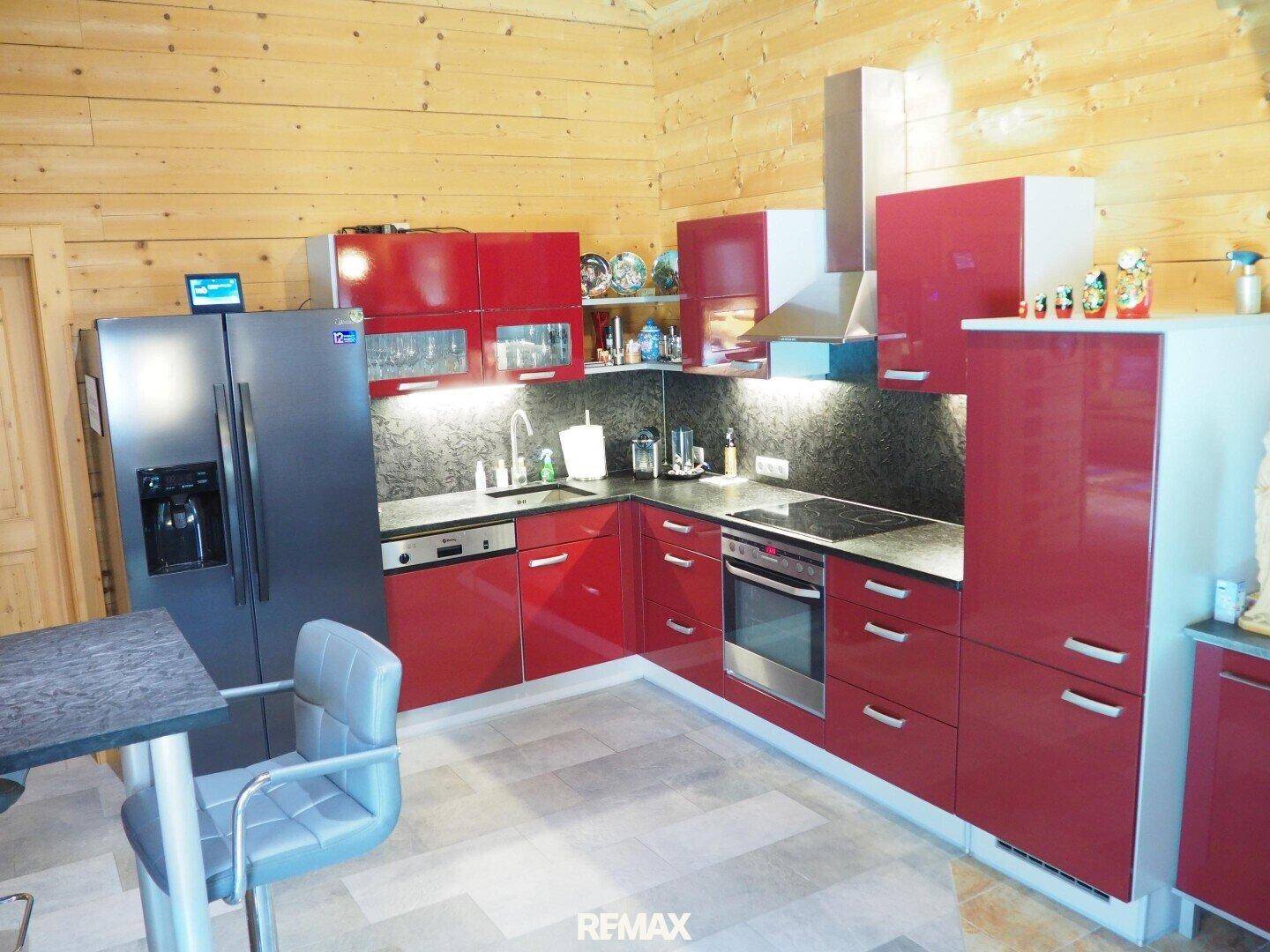Moderne rote Einbauküche mit Induktionskochfeld, Backofen und großem Kühlschrank.