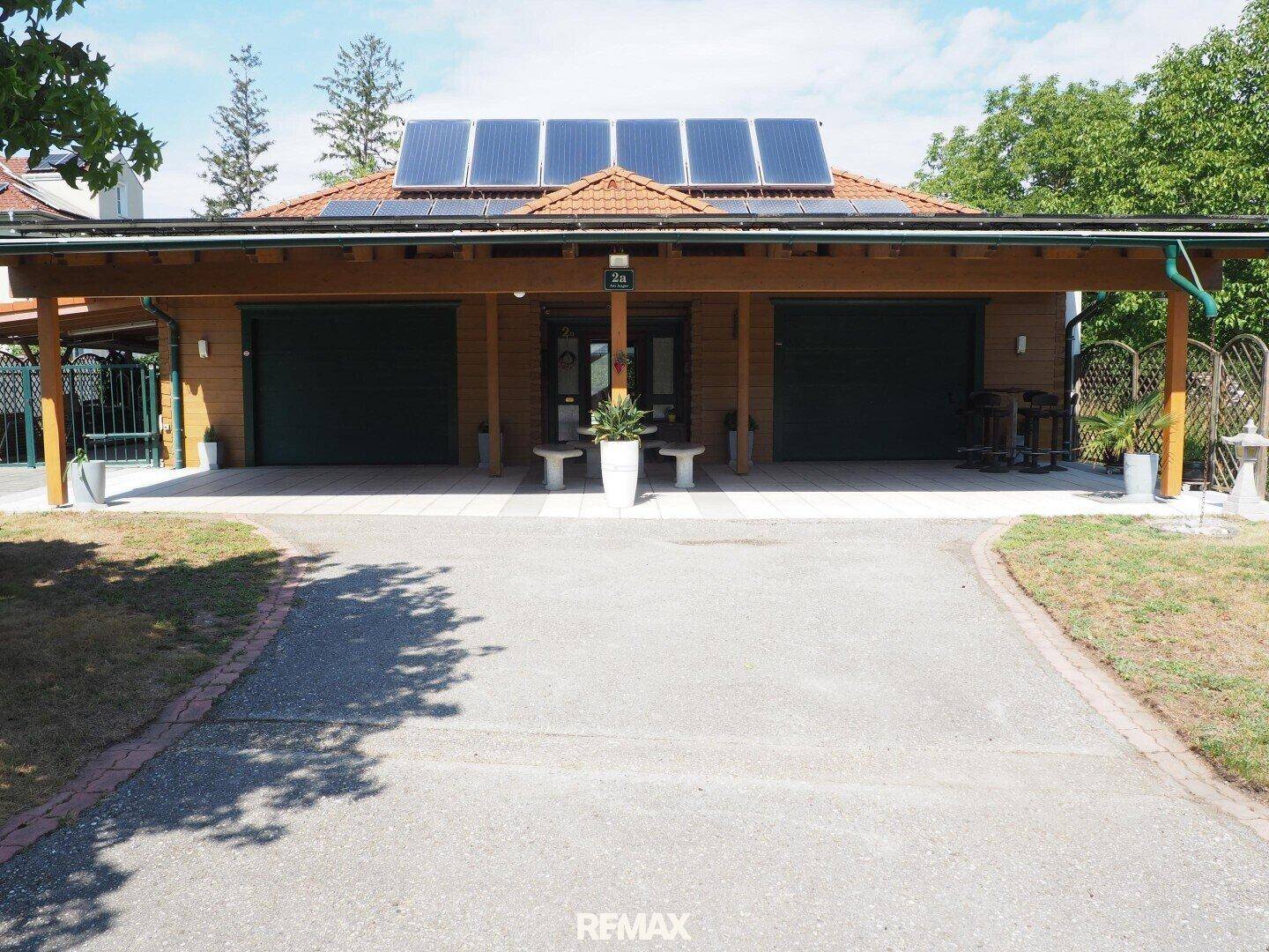 Frontansicht des Hauses mit Doppelgarage, überdachtem Eingang und Photovoltaikanlage auf dem Dach.