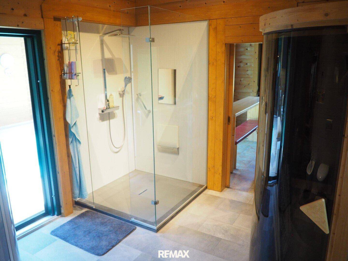 Geräumige begehbare Dusche mit Glasabtrennung und angrenzendem Solarium im Badezimmer.