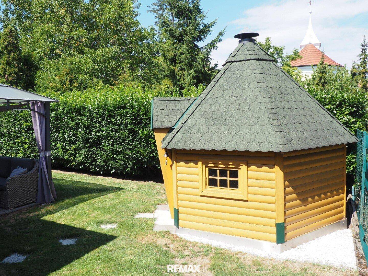 Gepflegter Garten mit einem charmanten Holzhaus und einem Pavillon.