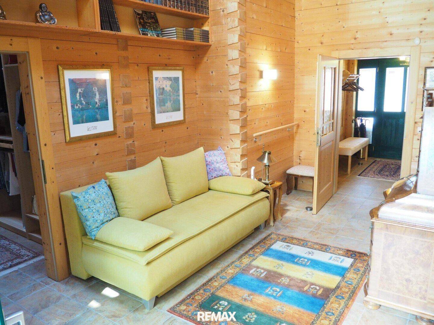 Heller Flur mit bequemer Couch, Bücherregalen und rustikalen Holzvertäfelungen.