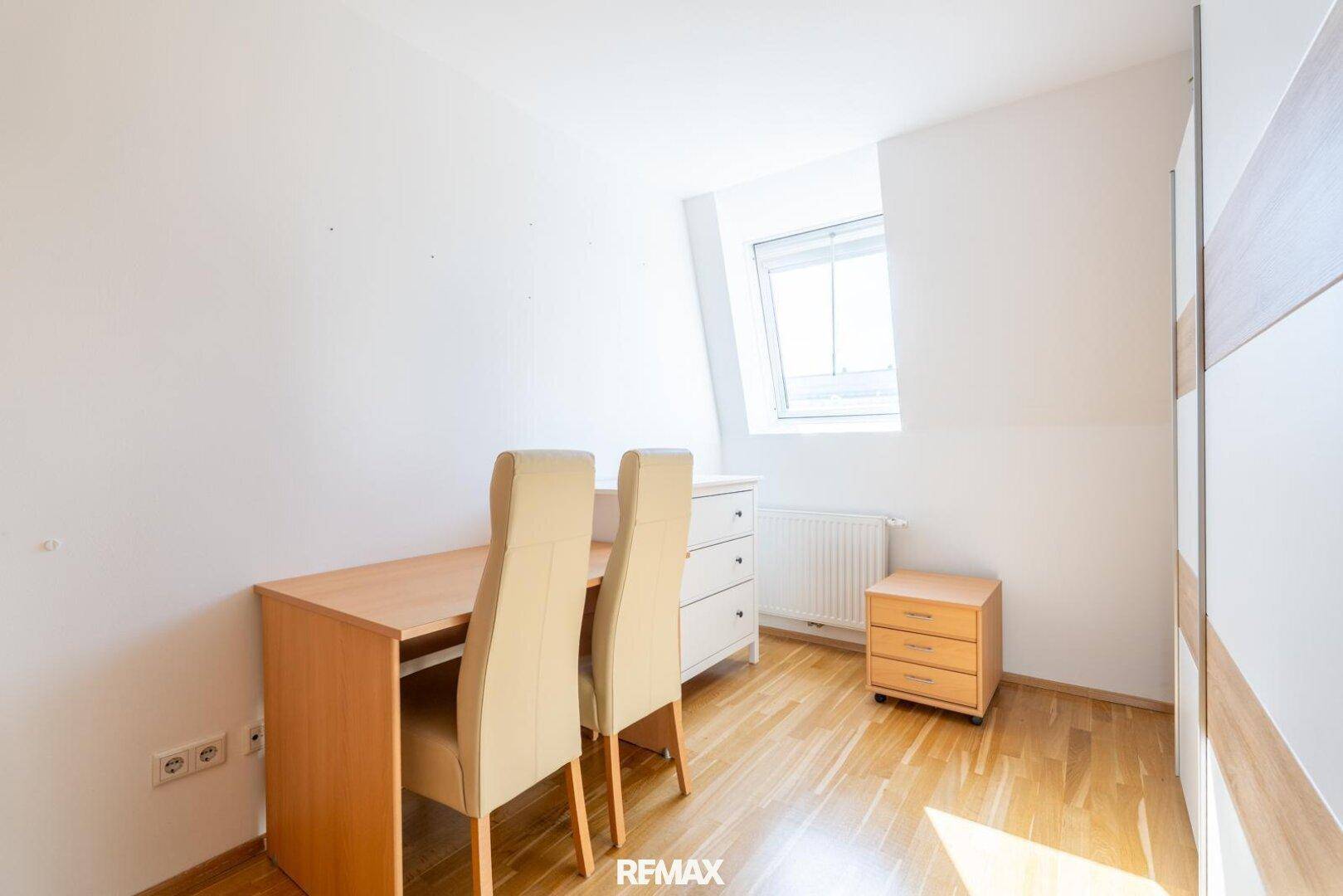 Kleines Zimmer mit Schreibtisch, Holzboden und Dachfenster, ideal als Arbeitsbereich.