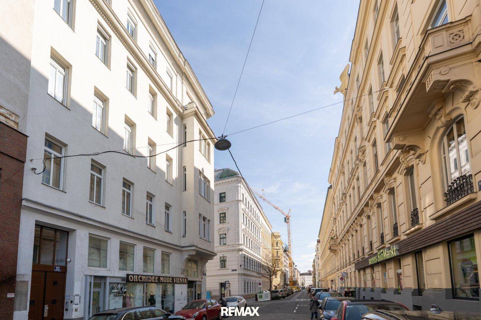 Historische Stadtstraße mit klassischen Gebäudefassaden und parkenden Autos.