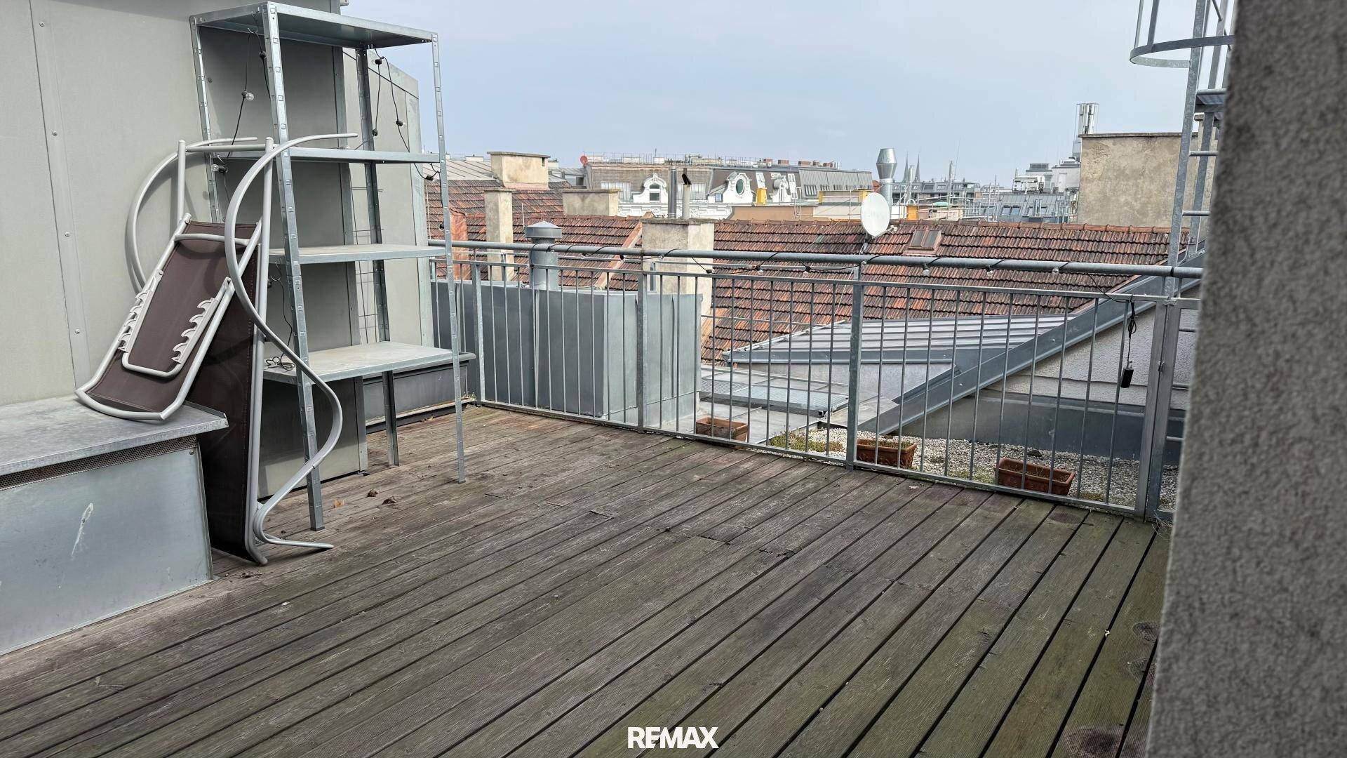 Geräumige Dachterrasse mit Holzboden und weitem Blick über die Dächer der Stadt.