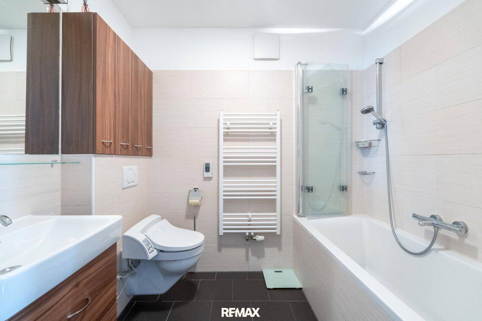 Modernes Badezimmer mit Badewanne, Dusche, WC und beheiztem Handtuchhalter.