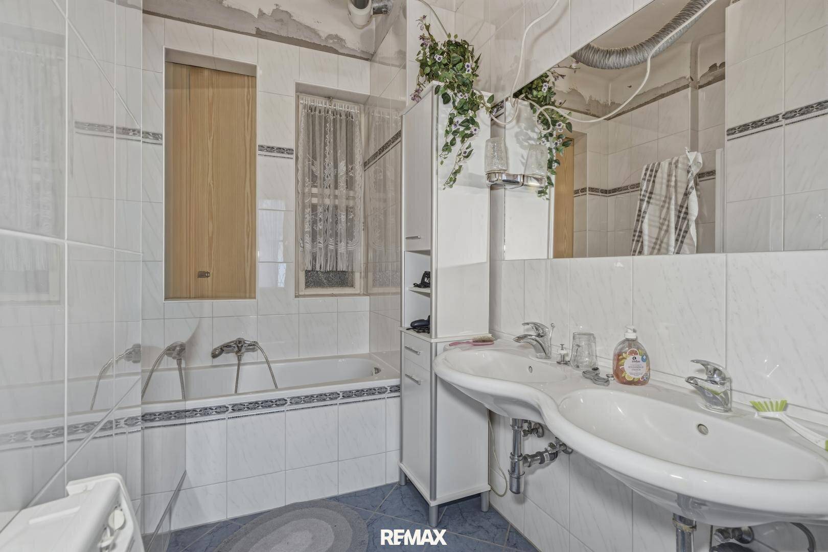 Badezimmer im Stil der 80er Jahre mit Badewanne, Waschbecken und blauen Fliesen.