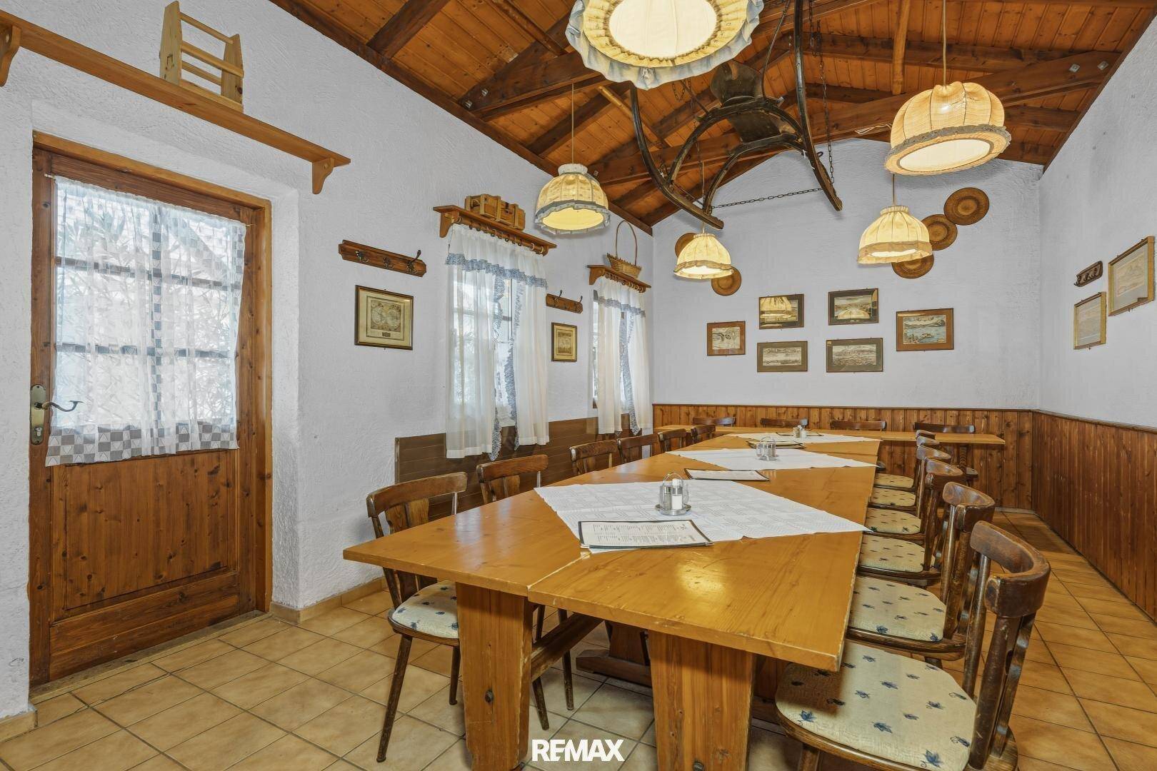 Großer Speisesaal mit Holztischen, Stühlen und einer Holzdecke, ideal für Veranstaltungen.