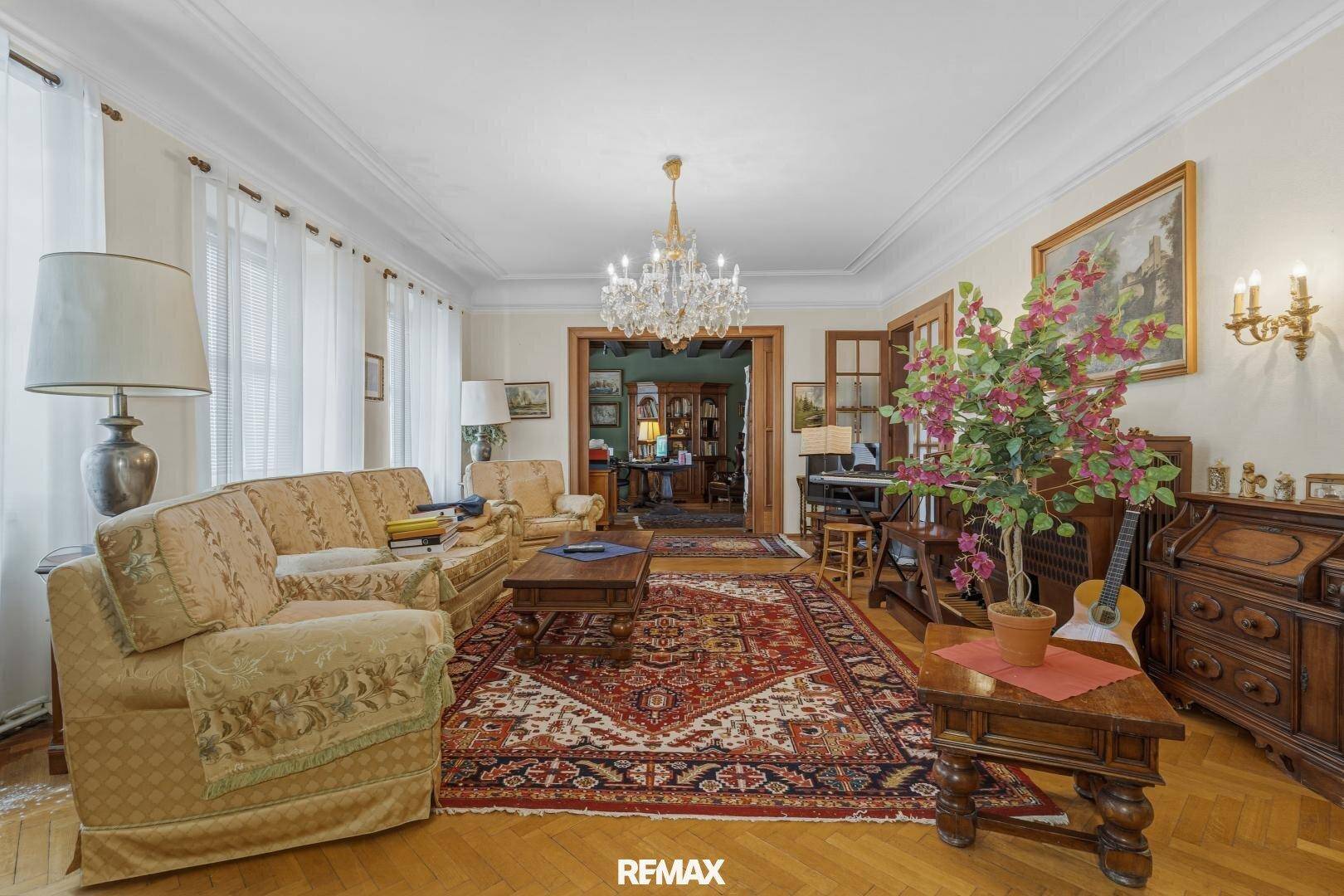 Helles Wohnzimmer mit traditionellen Möbeln, Kronleuchter und Parkettboden.