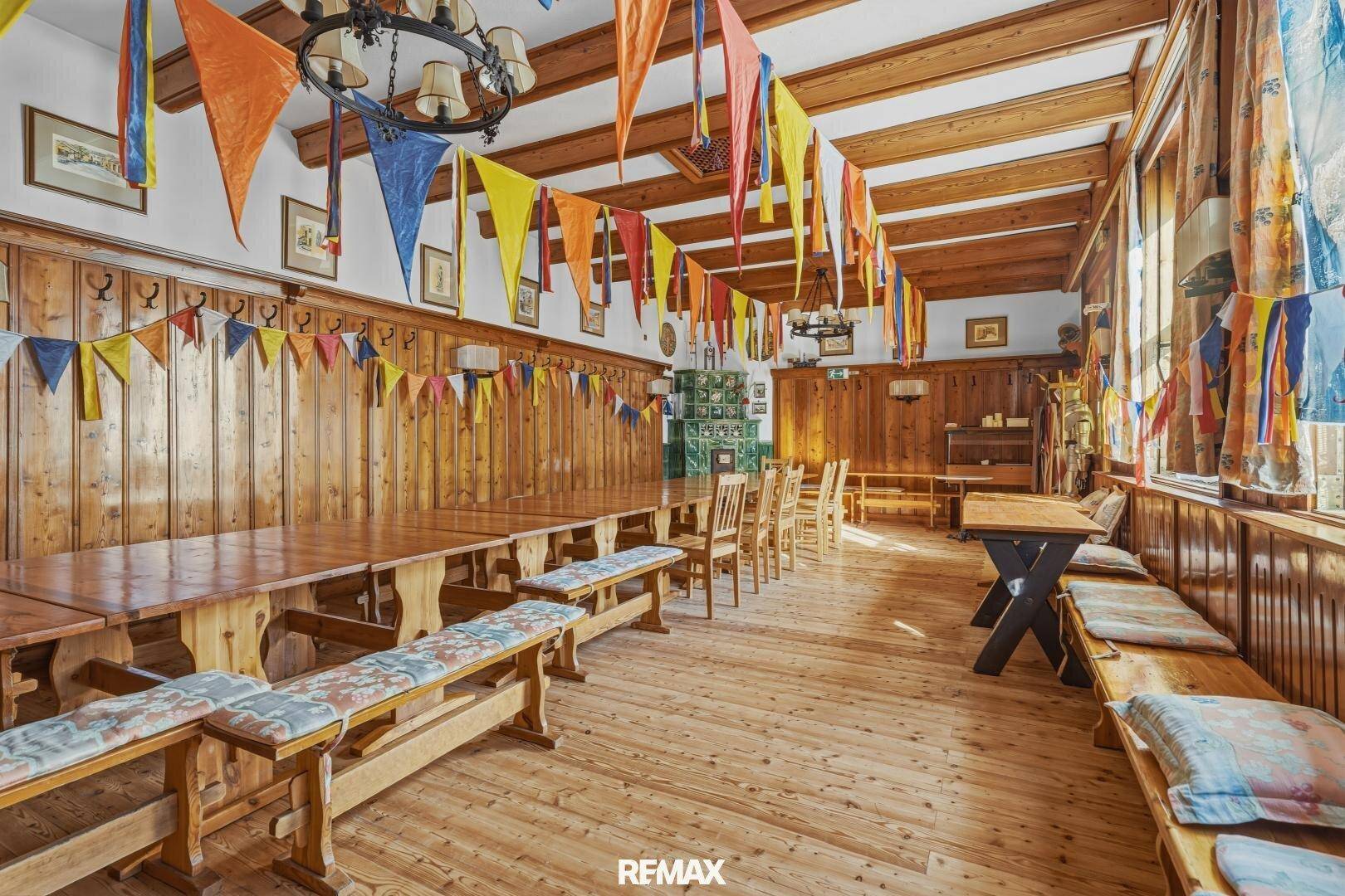 Großer Festsaal mit Holzvertäfelung, Holzboden und bunten Wimpelketten zur Dekoration.