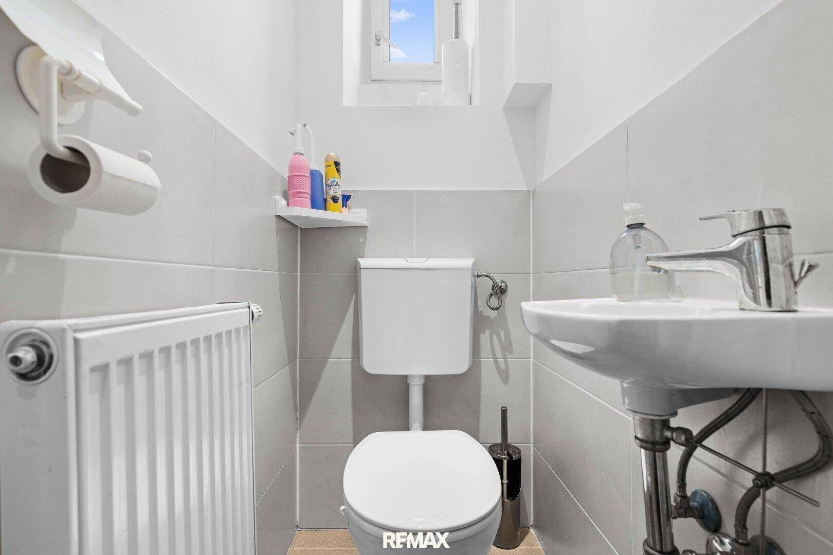 Kleines Gäste-WC mit Fenster, Toilette und Waschbecken.