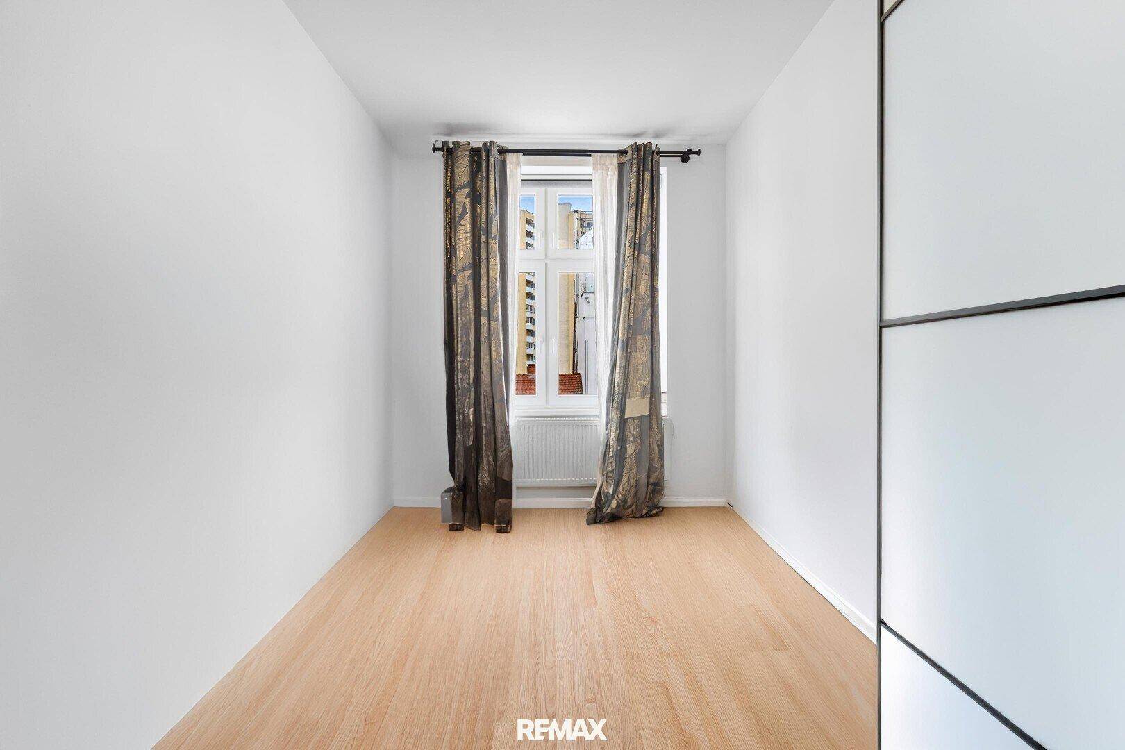 Leerer Raum mit Holzboden und Fenster, bereit zur individuellen Gestaltung.