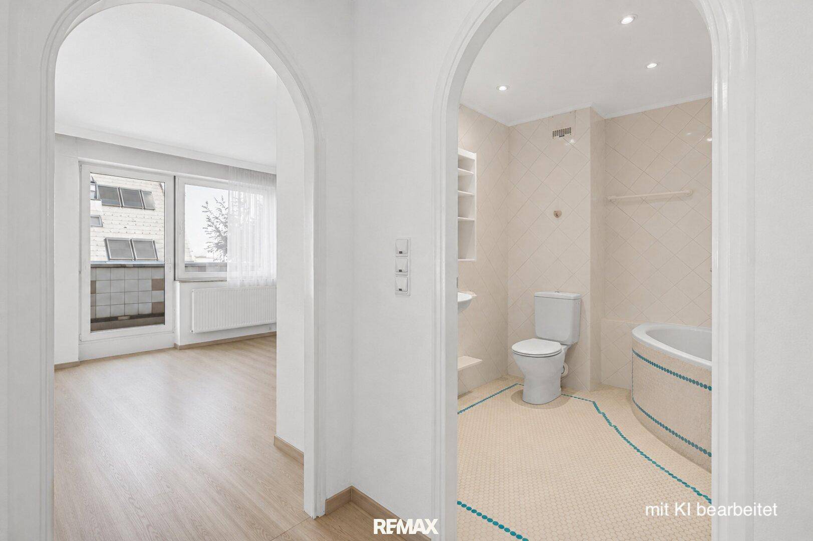 Badezimmer mit beigen Fliesen, einer Badewanne und einem WC, verbunden durch einen Rundbogen.