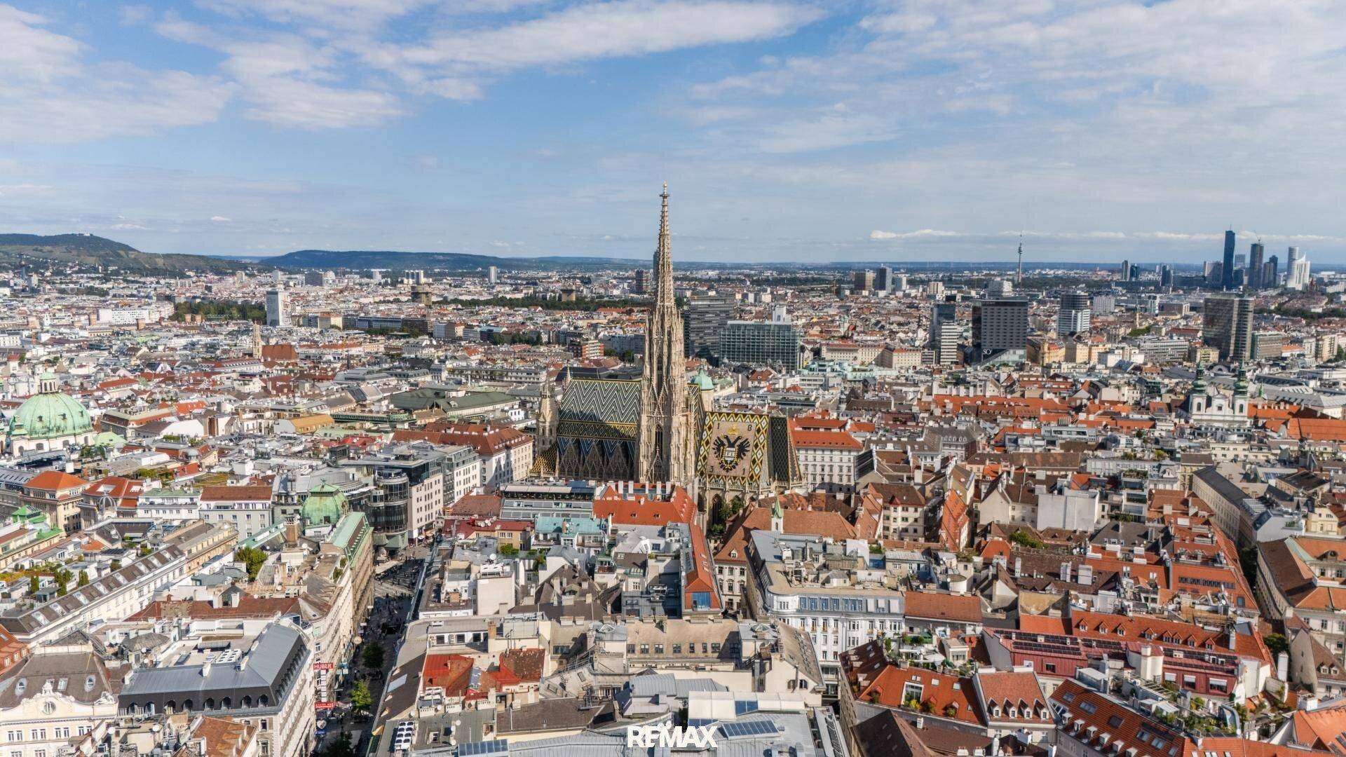 Panoramablick über die historische Stadt Wien mit dem Stephansdom im Zentrum unter blauem Himmel.