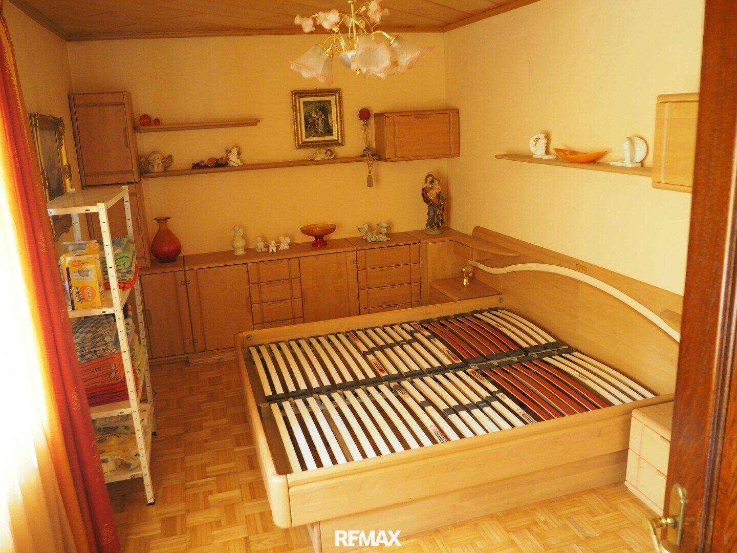 Schlafzimmer mit Holzbett, Einbauschränken und Parkettboden im Landhausstil.