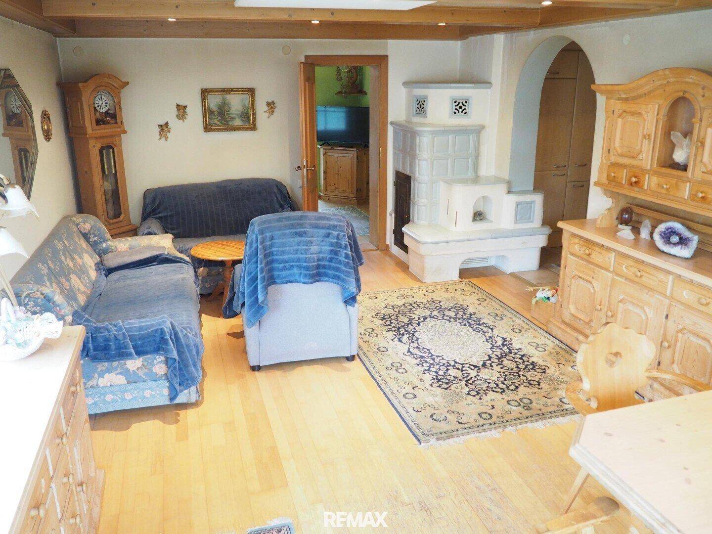 Geräumiges Wohnzimmer mit Holzboden, Kachelofen und traditionellen Holzmöbeln.