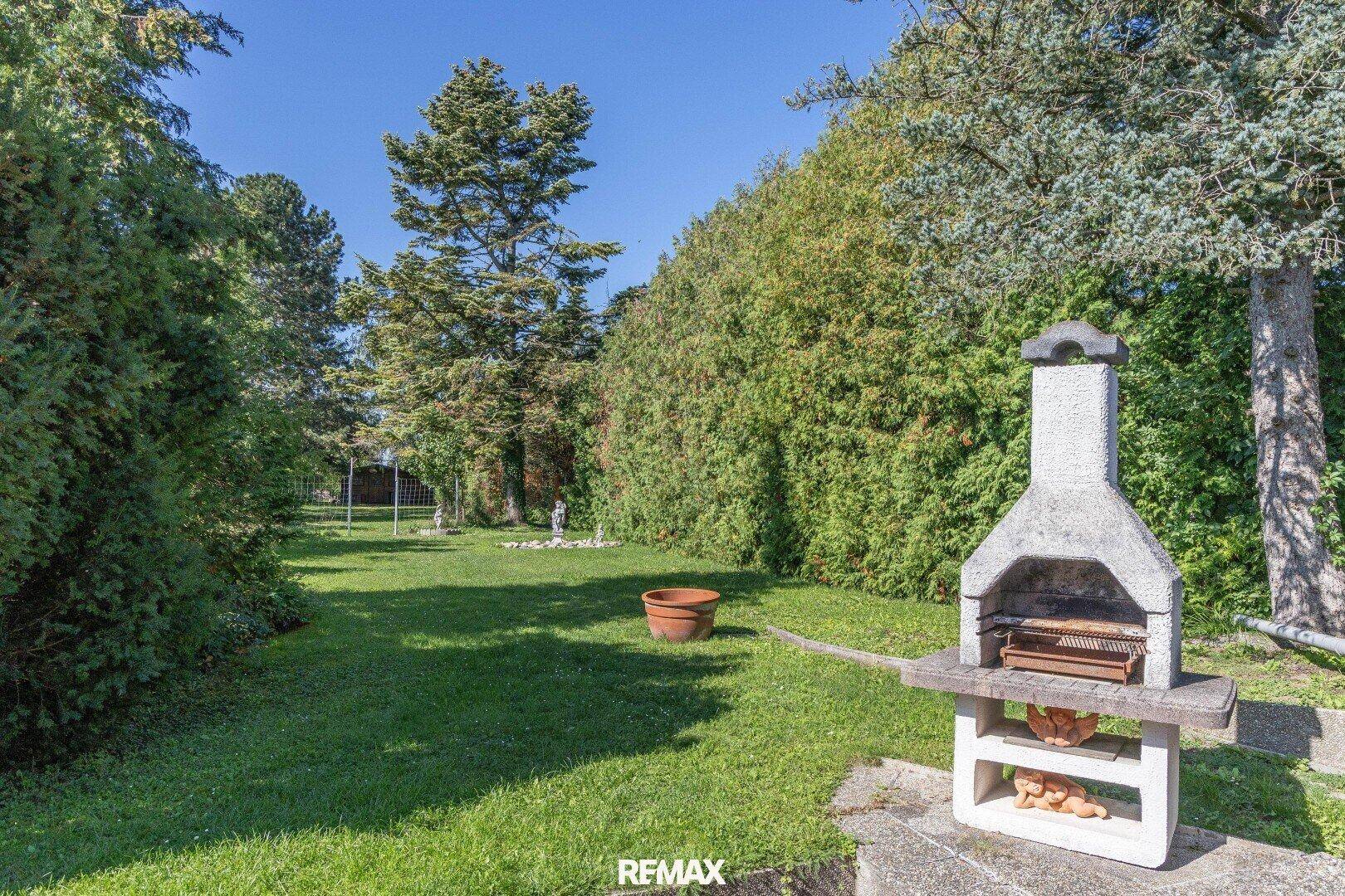Großer, gepflegter Garten mit Rasenfläche und einem gemauerten Grill für gesellige Abende.