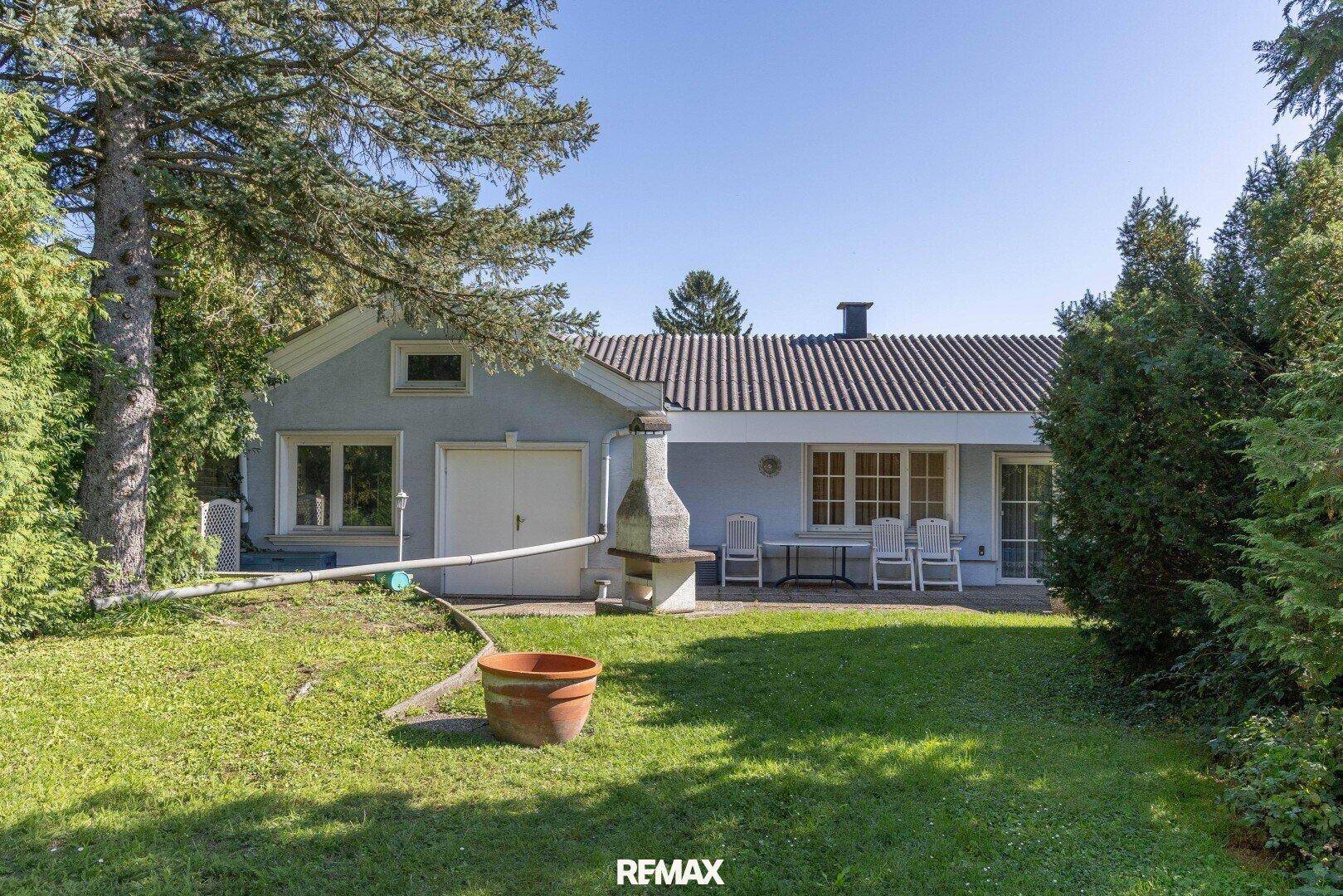 Rückansicht des Hauses mit Garten, Terrasse und einem gemauerten Grill.