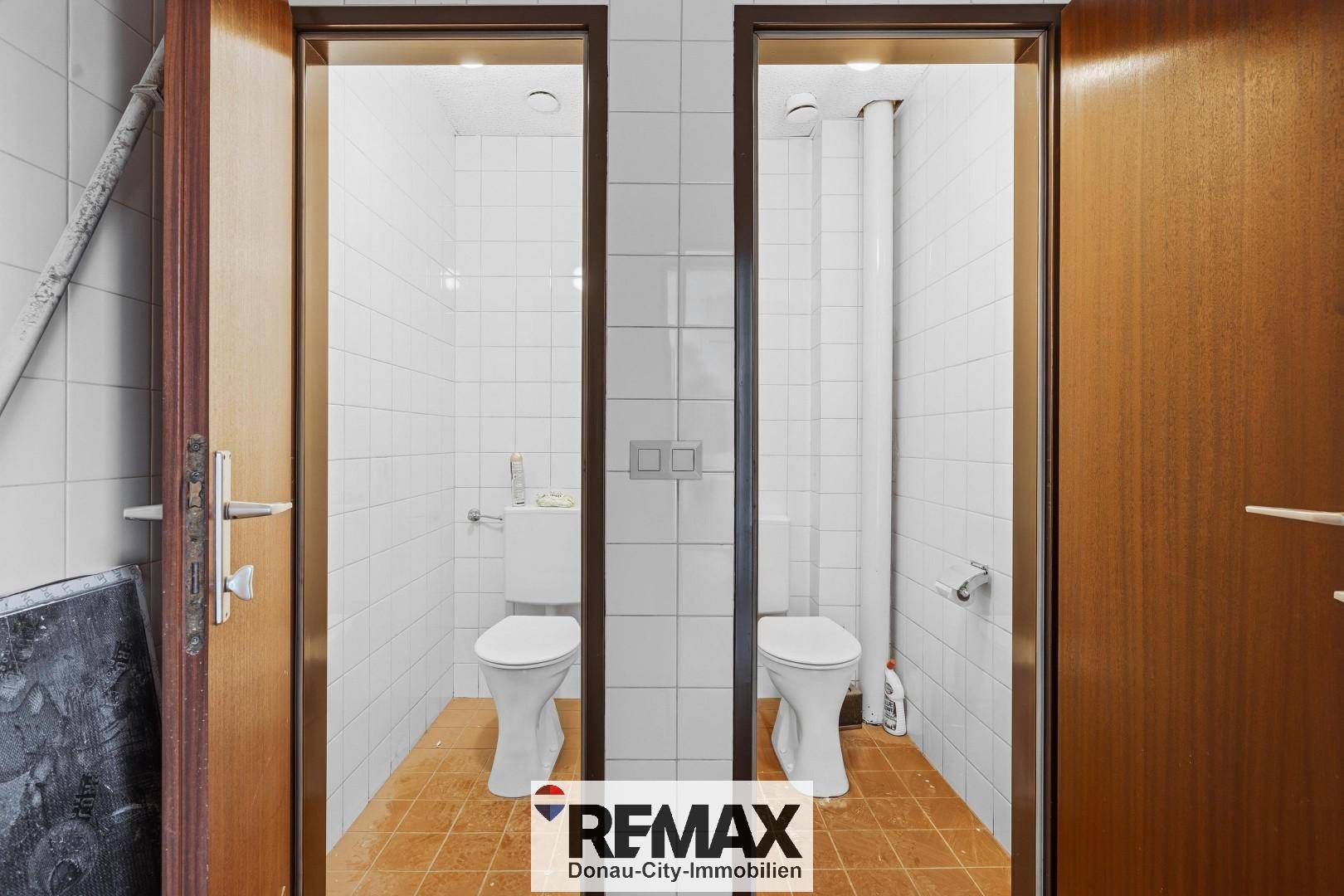 Zwei separate Toilettenräume mit weißen Fliesen und Terrakotta-Bodenfliesen, funktional eingerichtet.
