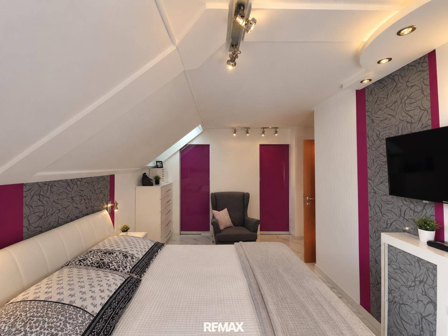 Gemütliches Schlafzimmer im Dachgeschoss mit schrägen Wänden, modernen Akzenten und indirekter Beleuchtung.