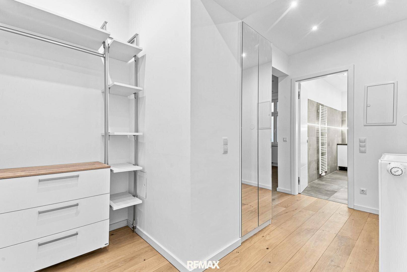 Heller Flur mit offenem Kleiderschrank und Spiegelfronten, führt zu weiteren Räumen.