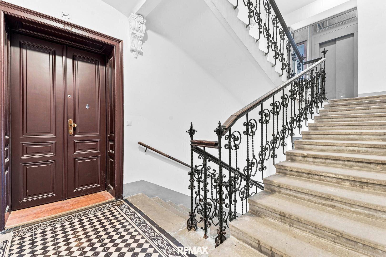 Historisches Treppenhaus mit kunstvollem Geländer, Steinstufen und Doppeltür zum Apartment.