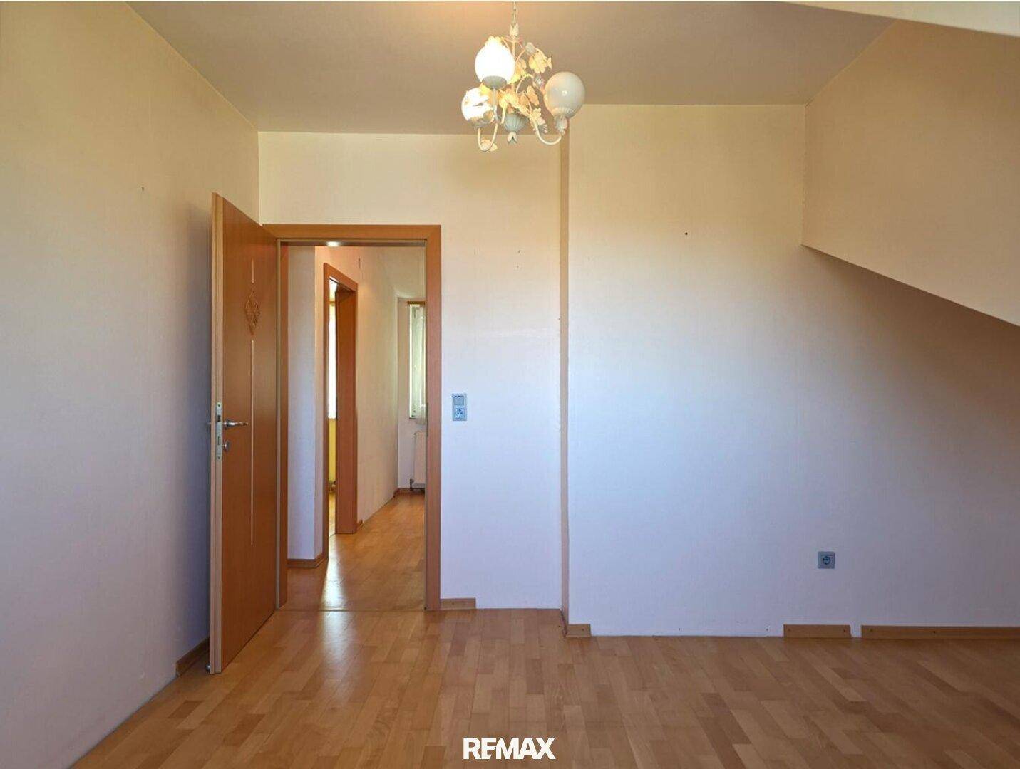 Geräumiges Zimmer mit Holzboden und Zugang zu weiteren Räumen.