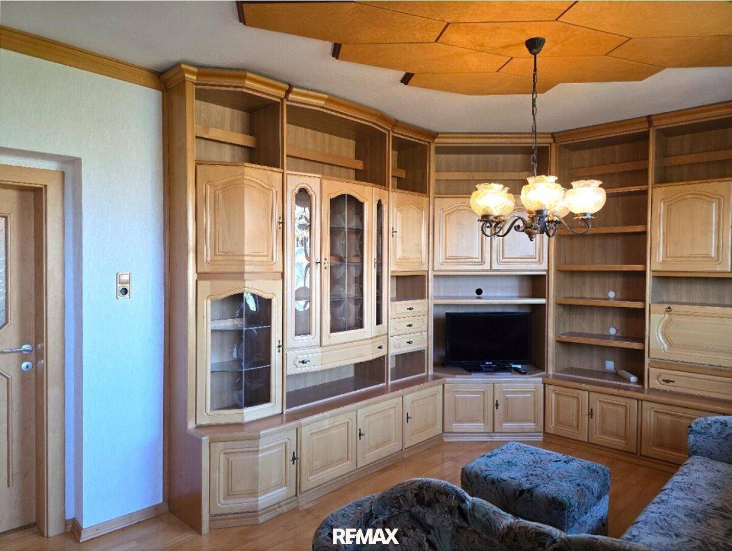 Geräumiges Wohnzimmer mit großer Holzschrankwand und Holzboden.