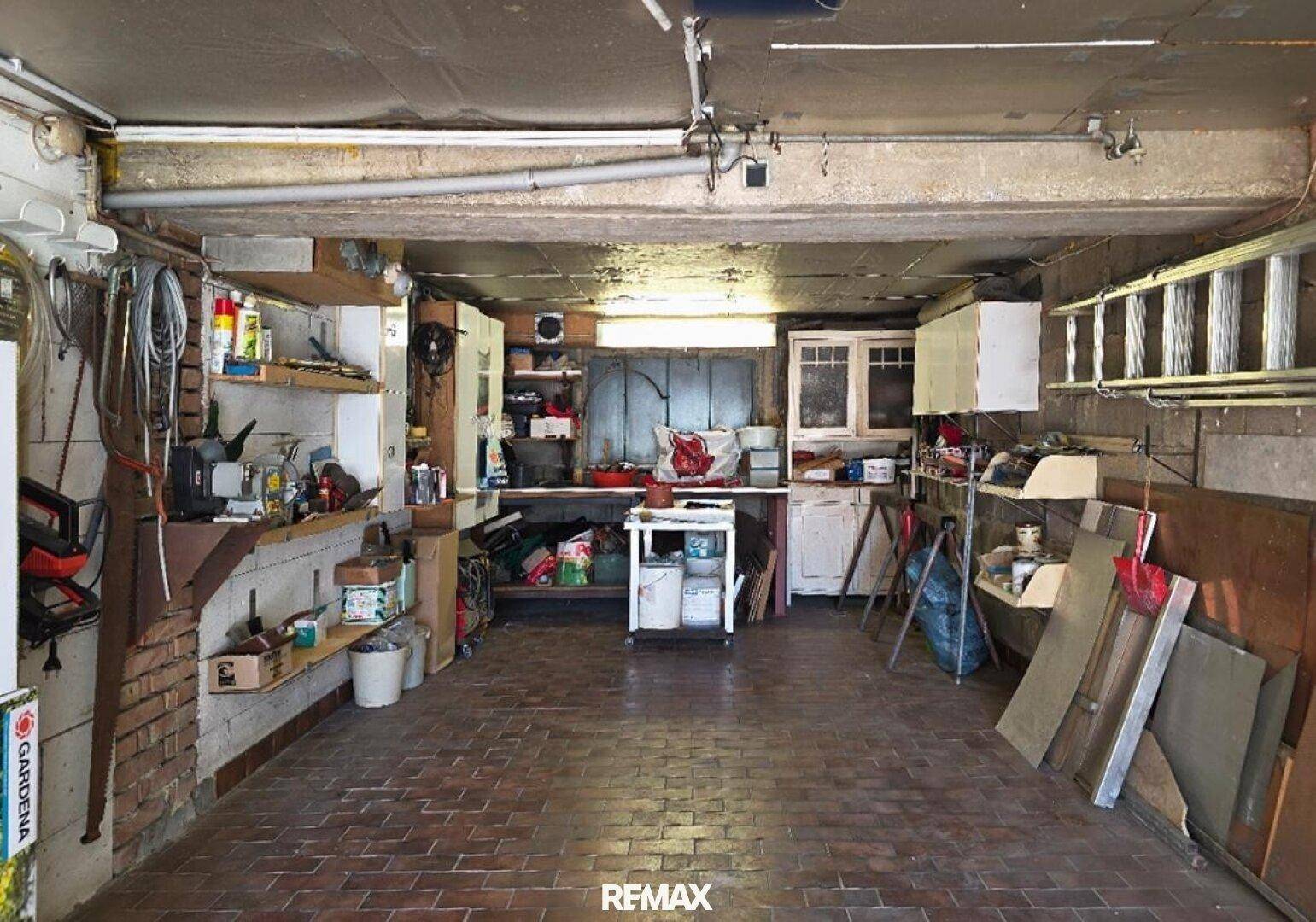 Geräumige Garage oder Werkstatt mit Ziegelboden, Regalen und viel Stauraum für Werkzeuge.