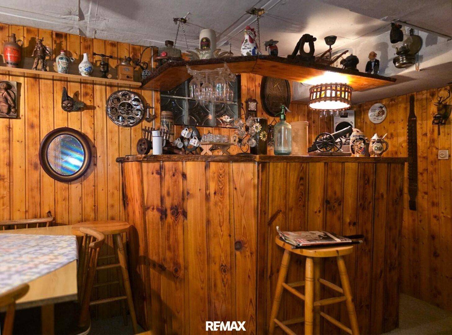 Rustikaler Hobbyraum mit Holzvertäfelung und einer gemütlichen Bar, dekoriert mit traditionellen Gegenständen.