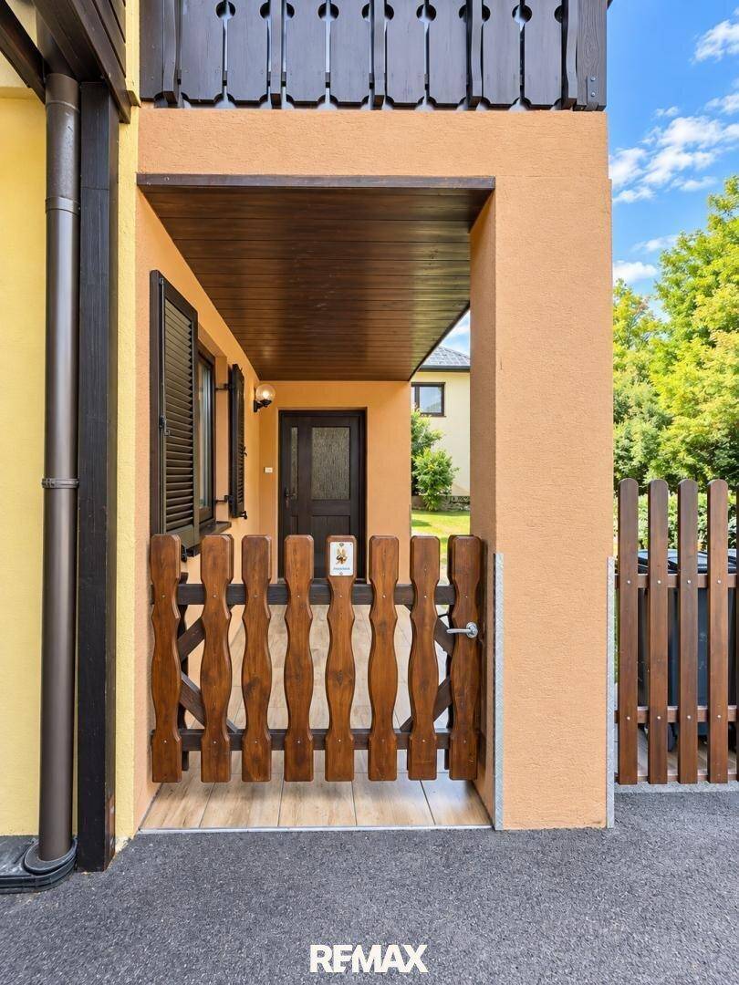 Eingangsbereich des Hauses mit rustikalem Holztor und dunklen Fensterläden.