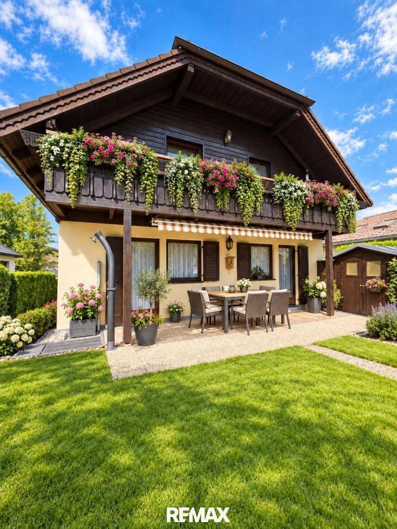 Charmantes Haus mit großer Terrasse, Gartenmöbeln und blühenden Blumenkästen.