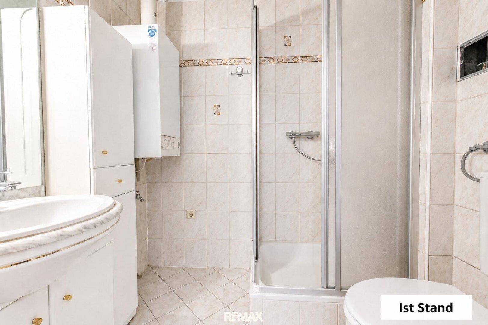 Helles Badezimmer mit Dusche, Waschbecken und beigefarbenen Fliesen, unmöbliert.