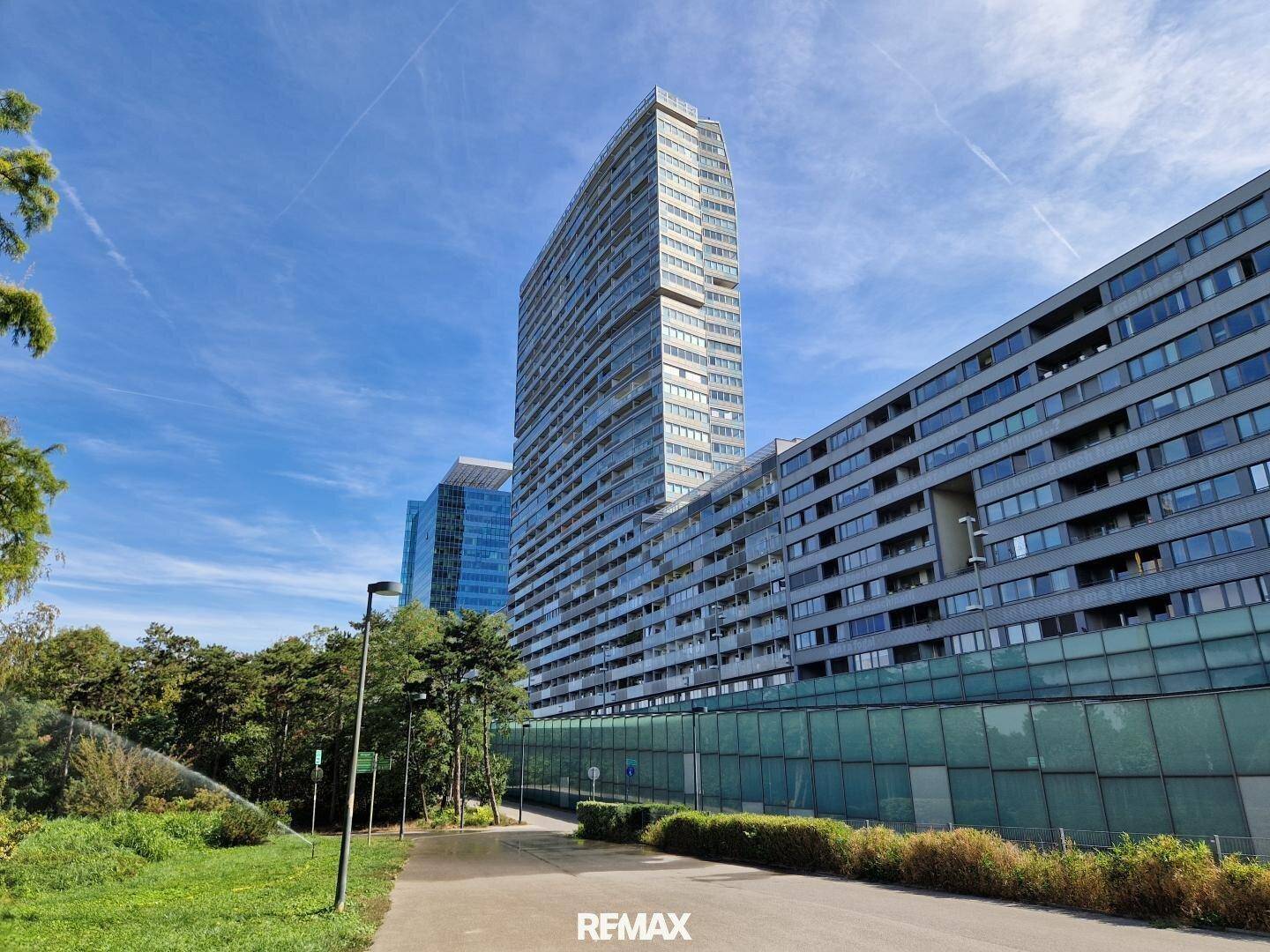 Moderne Wohngebäude mit markanter Architektur, eingebettet in eine grüne Umgebung mit Spazierwegen.