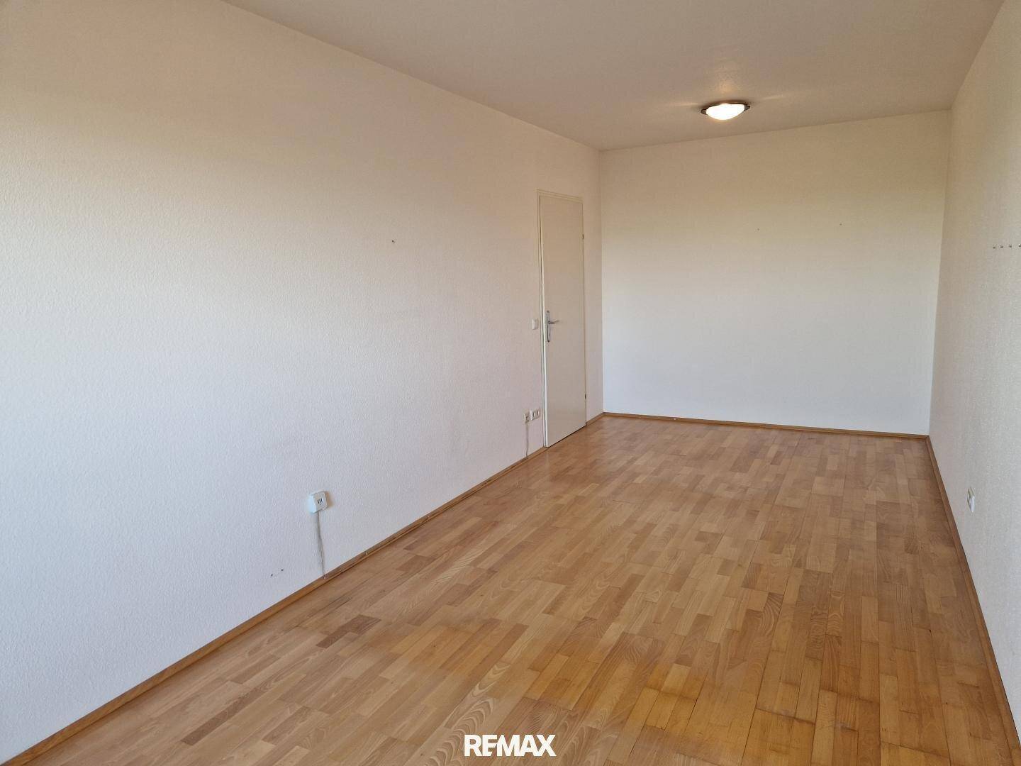 Helles Zimmer mit klassischem Holzparkettboden und weißen Wänden, ideal für Wohn- oder Schlafbereich.